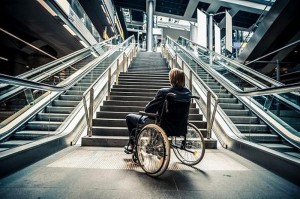 Una persona con disabilità motoria davanti a delle scale.