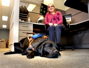 Una donna cieca nel suo ufficio assieme al suo cane guida.