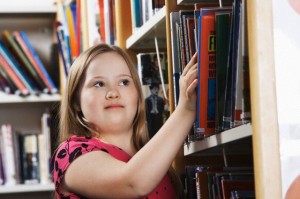 Una giovane donna interessata dalla sindrome di Down cerca un libro in uno scafale.