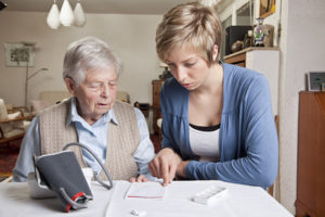 Una caregiver controlla che la persona anziana stia seguendo la propria terapia.