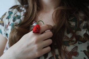 Una donna tine in mano una rosa appassita.