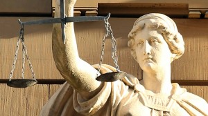 Una statua rifigurante una figura femminile tiene in mano una bilancia, una rappresentazione classica della giustizia.