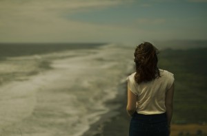 Una donna, ritratta di spalle, guarda le onde del mare (foto di Jonatan Becerra).