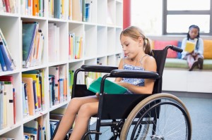 Una giovane studente con disabilità legge un libro davanti ad una libreria.
