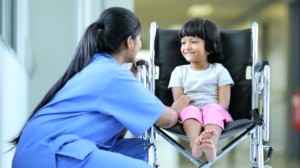 Un’infermiera parla con una bambina con disabilità motoria.