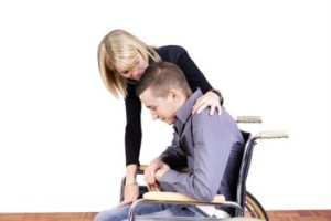 Una caregiver con un ragazzo con disabilità motoria.