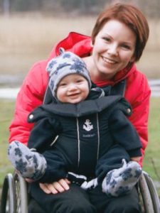Una madre con disabilità motoria tiene in braccio il suo piccolo bambino.