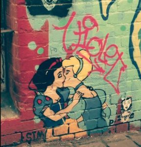 Un’opera street art raffigura un bacio appassionato tra due personaggi della Disney: Biancaneve e Cenerentola.