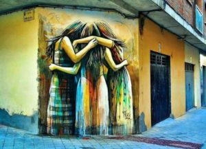 Un’opera della street artist italiana Alice Pasquini realizzata a Salamanca, in Spagna, raffigura tre giovani donne strette in un abbraccio.