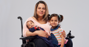 Una madre con disabilità motoria assieme ai suoi due figli, un neonato ed una bambina.