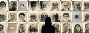 Una visitatrice del Museo della Follia osserva la griglia composta dai ritratti ritrovati nelle cartelle cliniche di alcuni ex-manicomi.