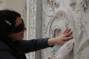 Una donna cieca esplora con le mani un bassorilievo. 