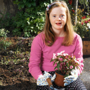 Un'adolescente con sindrome di Down fa giardinaggio. 