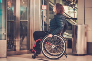 Una donna con disabilità motoria mentre aspetta l’ascensore. 