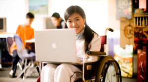 Una giovane con disabilità motoria utilizza un computer portatile. 