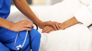 Un’infermiera tiene la mano di una paziente.